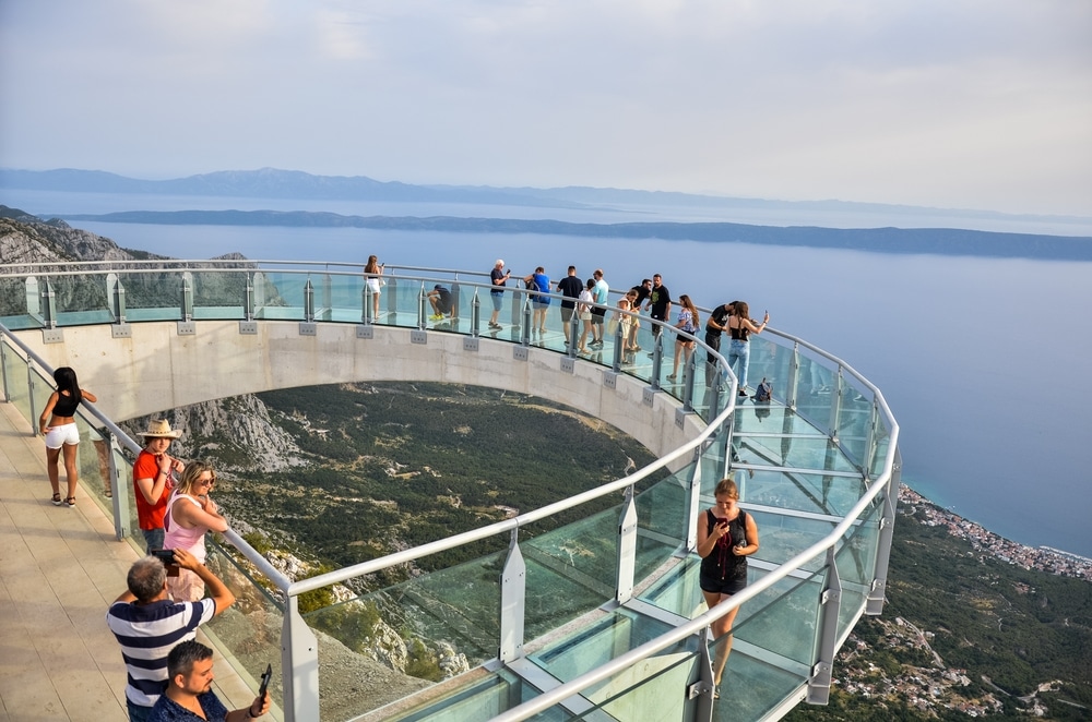 a group of people on a glass bridge over a body of water